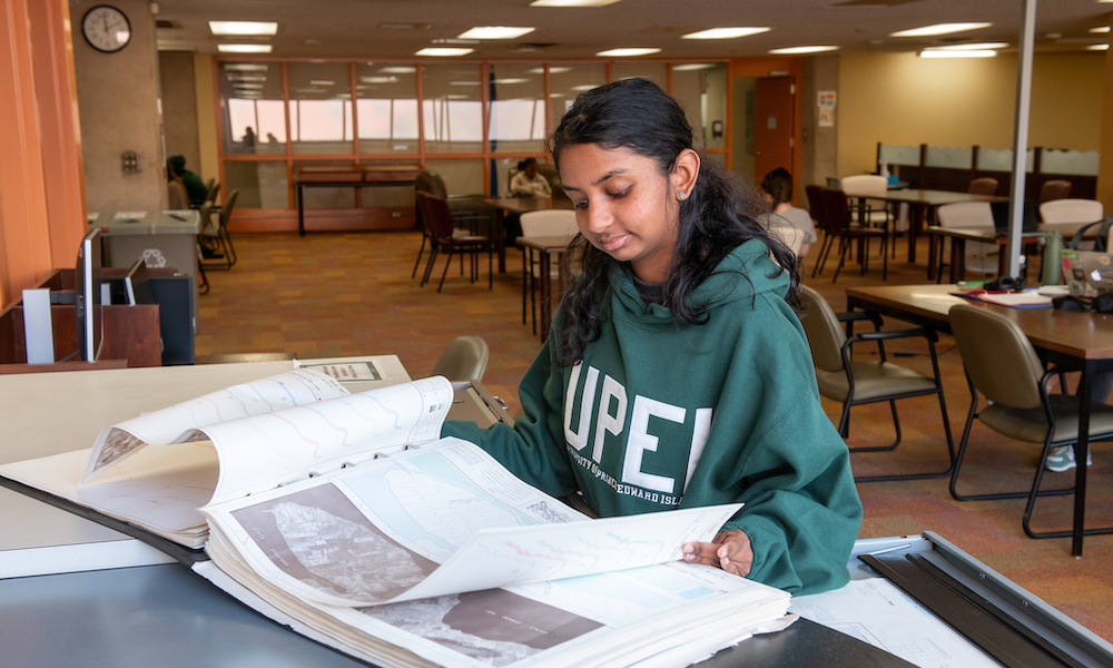 a student reading a large atlas