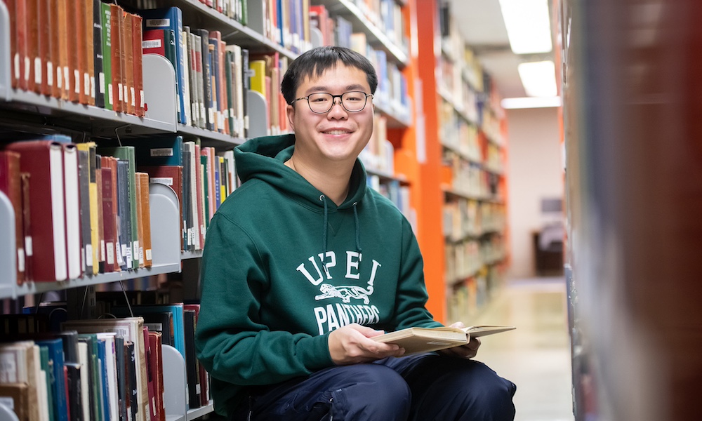 a student reading in the Robertson Library stacks