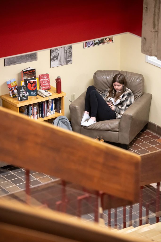 a student sitting in a leather chair using a phone